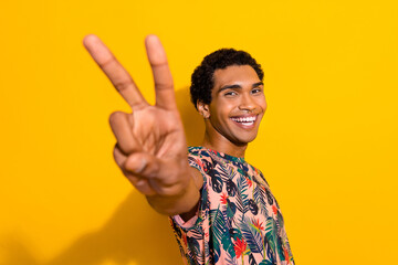 Photo of cheerful good mood guy dressed print t-shirt showing you v-sign isolated yellow color...