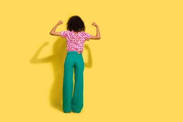 Full body rear portrait of confident lady raise fists flex biceps empty space ad isolated on yellow color background