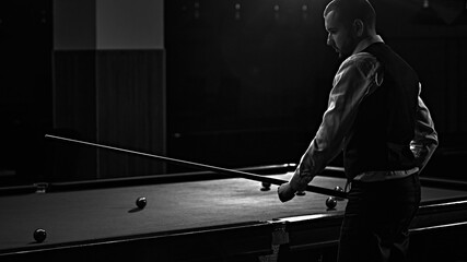 Man in waistcoat playing snooker game, billiards, monochrome image capturing intense focus. Luxury...