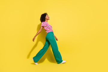 Full body profile portrait of cheerful gorgeous lady walking empty space isolated on yellow color...