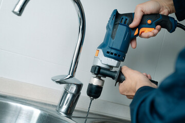 man drilling a hole in a metal sink - 741497344