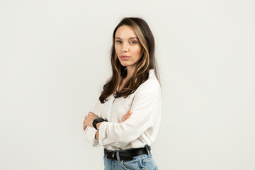 Stern looking young woman with arms crossed wearing a white blouse and jeans