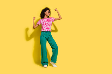 Full size portrait of positive pretty girl raise fists triumph look empty space ad isolated on yellow color background