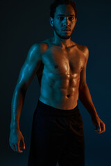 Fototapeta na wymiar appealing shirtless african american man in black sport shorts posing in gym and looking at camera