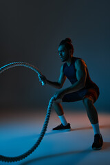 Fototapeta na wymiar attractive young african american man in black sport uniform training actively with battle ropes