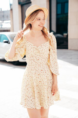Portrait of young beautiful smiling blond woman in trendy summer dress. Sexy carefree woman posing in street. Positive model outdoors at sunny day. Cheerful and happy.  In hat