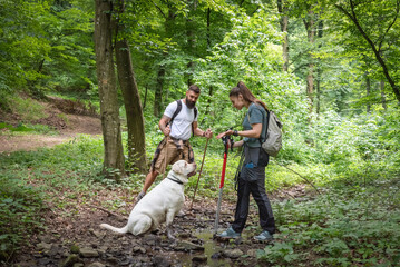 City escape. Young man and woman with their pet dog walking in the nature. Nature lovers couple...