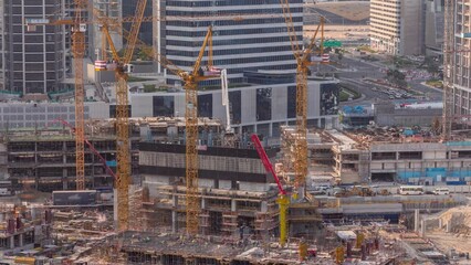 Large construction site with many working cranes timelapse. Top aerial view of big development of residential and office district in Business bay, Dubai. Workers in uniform on a reinforcement