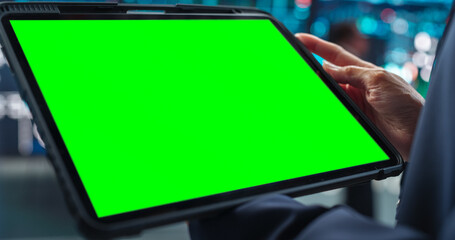 Person Holding a Tablet Computer with Green Screen Mock Up Display. Stock Exchange Application...