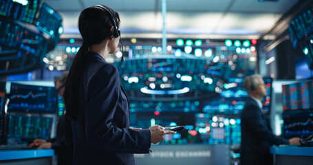 Portrait of a Young Beautiful Stock Exchange Broker Using Tablet Computer, Researching Real-Time Stocks Data, Analyzing Commodities and Exchange Market Charts. Professional Investment Banker in Office