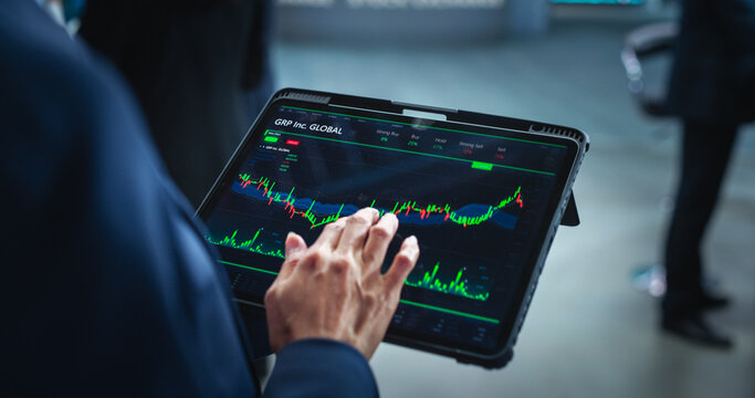 Tablet Computer Display with Real-Time Stocks, Commodities, Exchange Market Charts with Tickers. Anonymous Investment Trader Using Device in a Financial Business Office or Stock Exchange Floor - Powered by Adobe