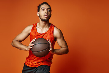 attractive athletic african american man in sportwear playing basketball actively on orange backdrop