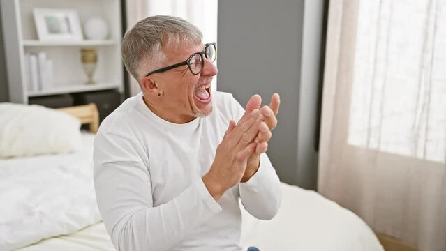 Madly ecstatic middle-age grey-haired man in pyjamas, wildly celebrating his thrilling win in the bedroom, arms raised in jubilant victory!