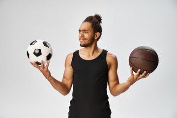 confused athletic african american man in sportwear holding football and basketball on gray backdrop