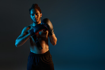 attractive shirtless african american man in sport shorts wearing boxing gloves while in gym