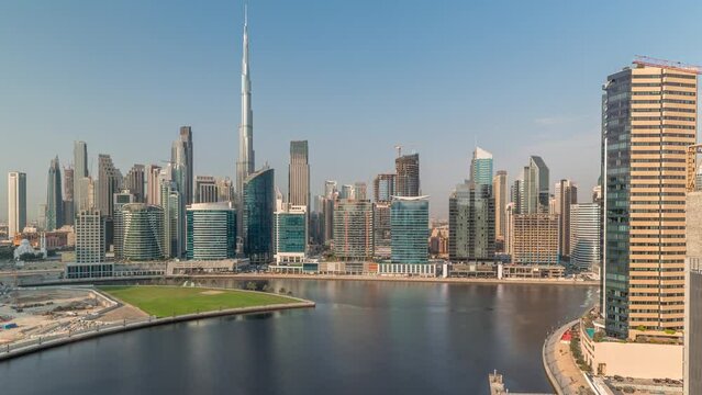 Aerial view to Dubai Business Bay and Downtown with the various skyscrapers and towers along waterfront on canal timelapse. Construction site with cranes. Clouds on a sky
