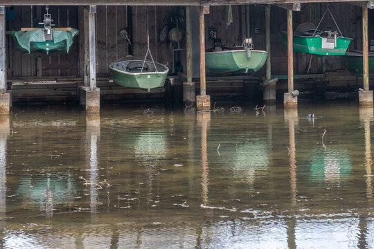 Bootshaus mit geparkten Booten in der Luft und Spiegelung im Wasser