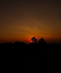 Beautiful sunset scenery view of sun hiding behind clouds, golden hour wallpaper, nature photography, natural scenic background, silhouette of trees