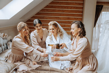Photo with bridesmaids drinking champagne from glasses in the morning in a beautiful hotel. Photo...