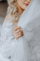 cropped portrait of bride holding her veil with hand with wedding ring on finger. Beautiful blonde bride