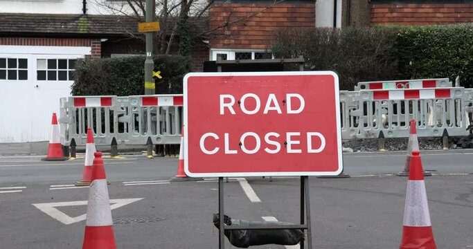 Red road closed sign on a busy road with the traffic running behind on a busy road in a residential area in UK.