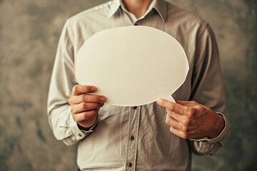 A person holding a cardboard speech bubble in front of him in a studio shot