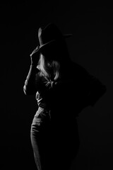 Dark studio portrait of young elegant sexy woman with a white hat and white shirt black and white photo