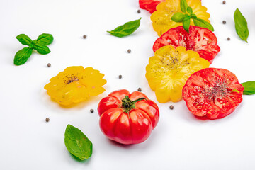 Colorful Heirloom tomato harvest. Ripe ribbed vegetables with fresh basil leaves. Wooden background