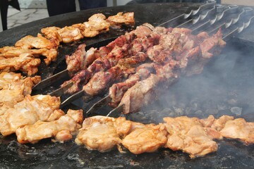 Kebab meat skewers grilling and chicken on fire at backyard. Marinated shashlik, meat grilling on metal skewer. Greek grill food. Outdoor barbecue cooking. Street food concept
