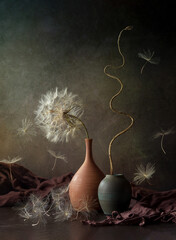 Modern still life with a large dandelion in a clay vase on a dark background