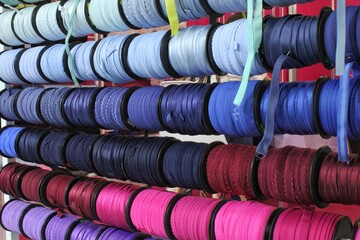 Bobbins with various colorful ribbons on counter in store. Needlework and sewing supplies. Colorful...