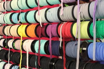 Bobbins with various colorful ribbons on counter in store. Needlework and sewing supplies. Colorful...