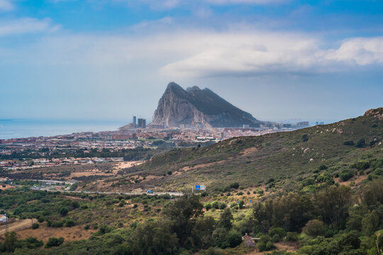 Viewpoint to hill along highway with architecture of La L&iacute;nea de la Concepci&oacute;n with fog and headland of The Rock Gibraltar on the horizon, SPAIN