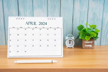 April Monthly desk calendar for 2024 year and alarm clock.