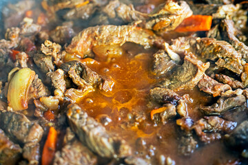 Obraz na płótnie Canvas cook meat cut into pieces in a frying pan with vegetables, top view. Cooking at home in the kitchen