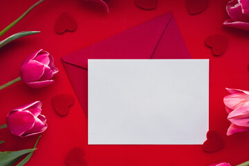 Empty white envelope copy space for your text or design with beautiful pink tulip bouquet on red background. Red small heart. Love romance Valentines day. Template mock up for holiday spring greeting
