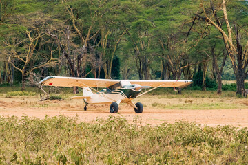 A small aeroplane on a runway in the wild at Lake Nakuru National Park in Kenya - obrazy, fototapety, plakaty