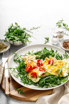 Fried eggs, omelette with onions, tomatoes and fresh arugula salad