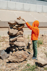 A child builds a pyramid of stones on the shore.