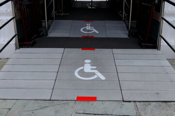 White sign wheelchair on gray slope floor entrance building, Thailand.
