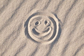 Happy smiley drawn on the white wavy sand, close up. Concept of good emotions, happiness, positive...