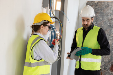 team electrical engineers or technicians is professionally inspecting the wiring and systems in the building. Check electrical equipment to meet safety standards. Use a tablet to check buildings.