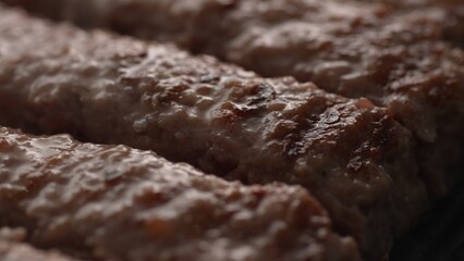 Grilling Cevapcici Sausages in Pan. Close-up, shallow dof.