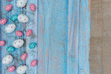 Wooden background with pickled paint and painted Easter eggs and flowers on the side.