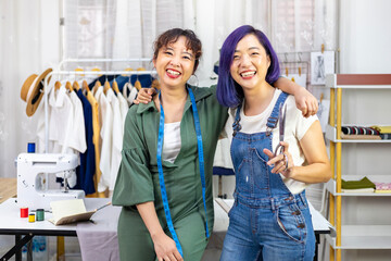 Portrait of smiling Asian fashionable freelance dressmaker team in their artistic workshop studio for fashion design and clothing business industry
