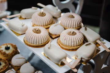 Delicious wedding reception in a restaurant. Candy bar with desserts for celebrating a birthday party. Table with cake, sweets, candies, and dessert. A place for text.