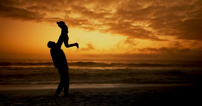 Father, child and lift in beach with silhouette, sunset and care with games with clouds in nature on holiday. Person, kid and bonding with love, waves and family at dusk for outdoor vacation with sky