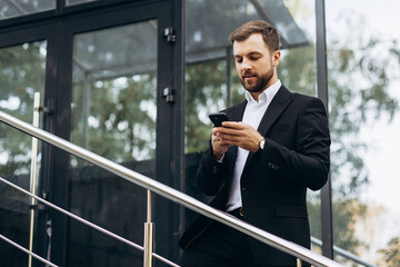 Business man using mobile phone and standing by office center