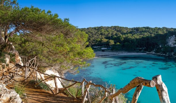 landscape view of the idyllic Cala Macarella in southern Menorca with a hiking trail in the foreground