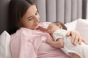 Fototapeta na wymiar Mother with her sleeping newborn baby in bed